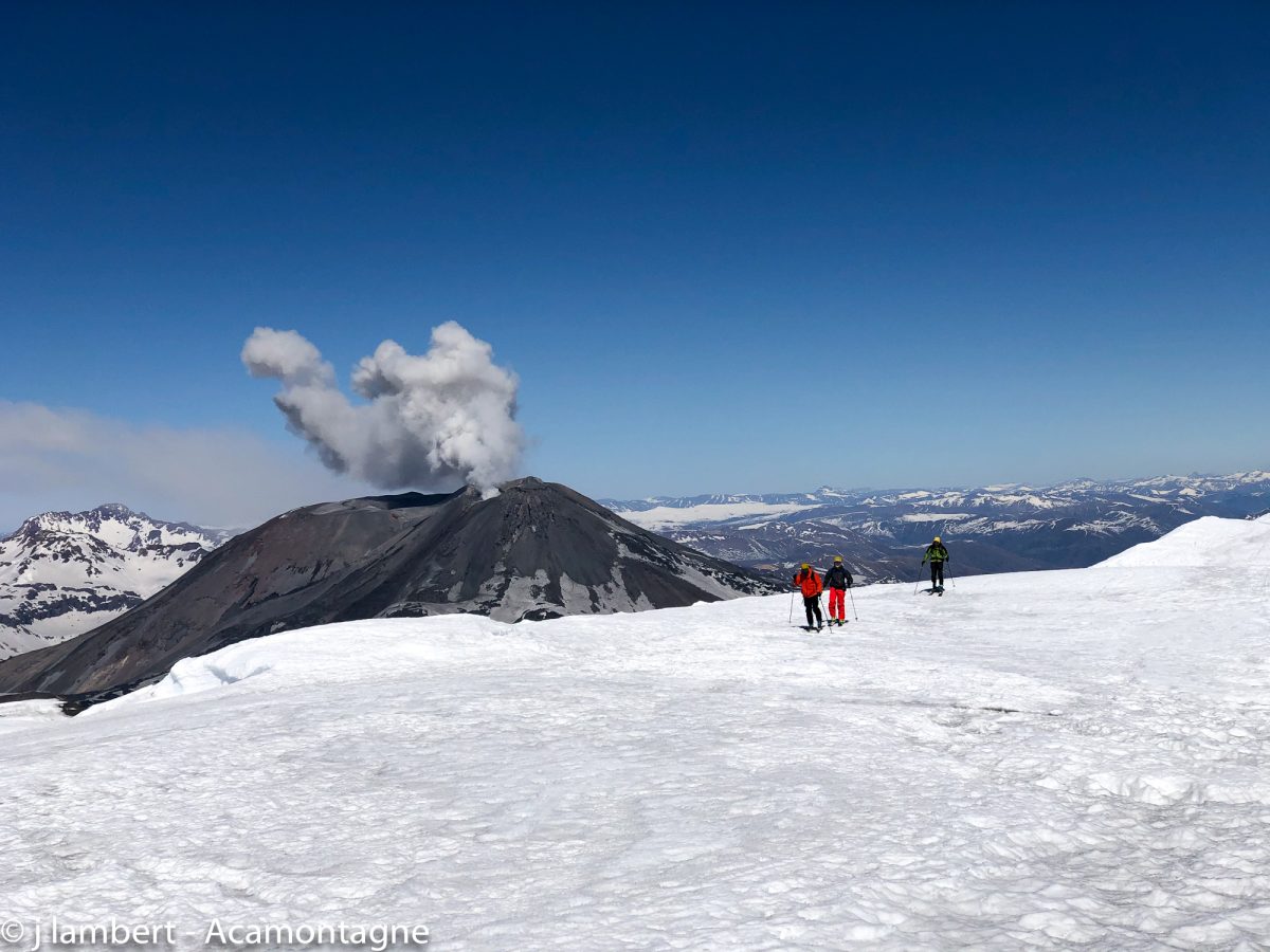 Arrivée au sommet du volcan. Le volcan en éruption est visible en arrière plan.